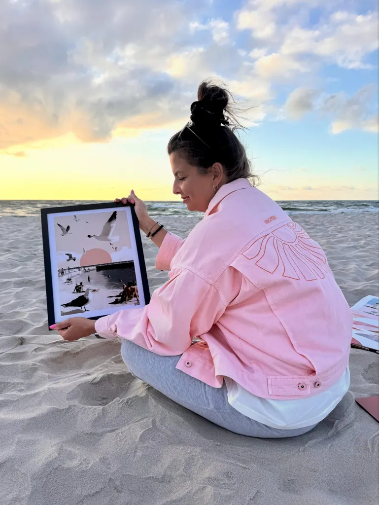 Kasia Puchowska na plaży z oprawionym plakatem w dłoniach